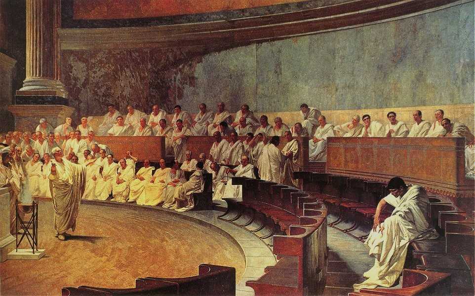 A realistic painting of maybe fifty or so men in white togas in a semicircular room. Cicero stands on the floor of the senate to the left of the painting; Catiline sits alone to the lower right, surrounded by empty chairs. The rest of the senators crowd in the benches towards the upper left.